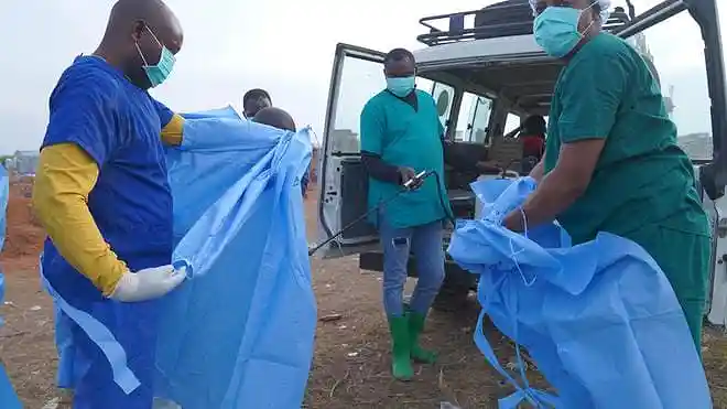 A health worker sprays disinfectant on a colleague after an Ebola burial service in Bunia, Ituri province, eastern Congo.