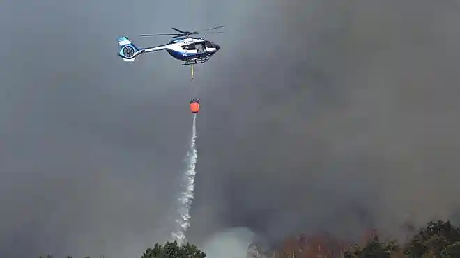germany wildfire Police helicopter carrying an external water tank fights a forest fire in Hürtgenwald, Germany.