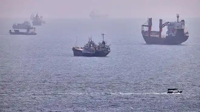 Cargo ships and commercial vessels anchored in the Strait of Hormuz off Bandar Abbas, Iran.