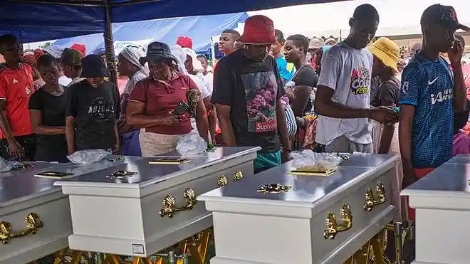 Family members walk past caskets during a memorial service for victims of the Lake Kariba ferry disaster in Zimbabwe.
