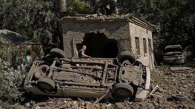 A local resident stands beside destroyed cars after an overnight Russian missile and drone attack in Kyiv, Ukraine.