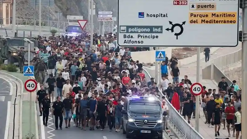 Spanish police officers and soldiers escort a large group of migrants in Ceuta toward the border with Morocco during efforts to remove them from Spanish territory.